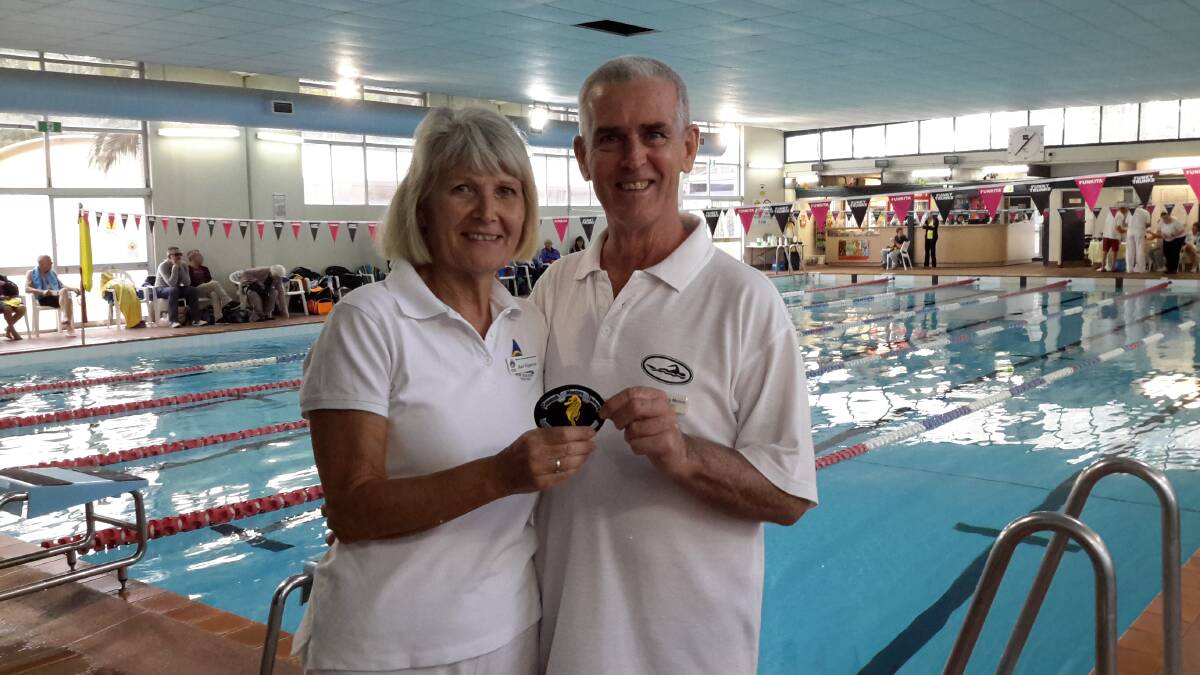 MILESTONE: Chief referee Ruth Fitzpatrick presents Cessnock's Dennis Moore with a patch at his 300th Masters Swimming carnival.