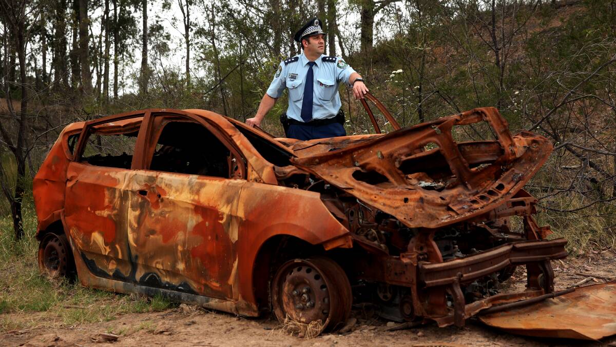 DANGER: Central Hunter acting crime manager Detective Sergeant Mitch Dubojski with an abandoned car that has been torched. Picture: Simone de Peak