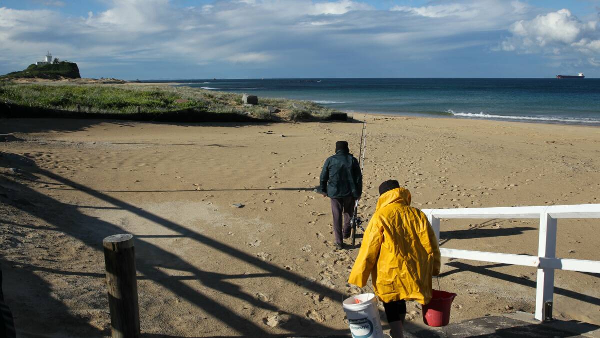 BRAVE: Fishermen heading to the water at Nobbys Beach on Friday. Picture: Max Mason-Hubers