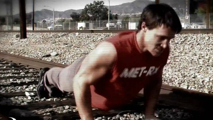 A screenshot from a Greg Plitt fitness video showing him working out on train tracks. Photo: YouTube