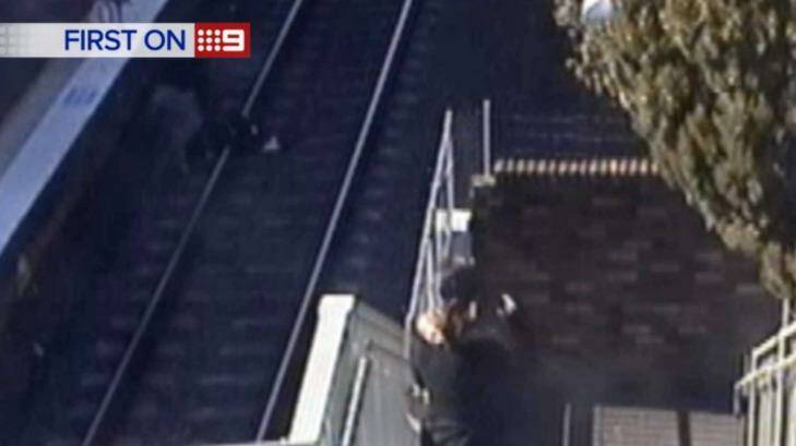 A grandfather picks his granddaughter up off the tracks after her pram rolled off a rail platform in western Sydney. Photo: Nine News