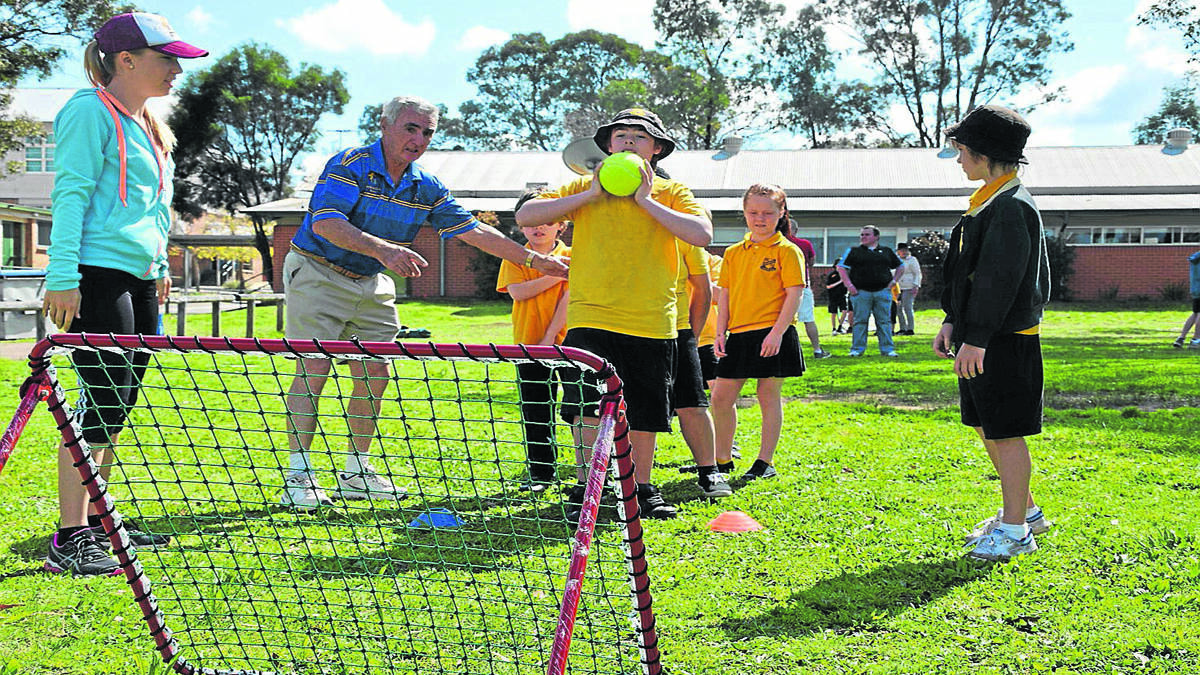 Don Stephens from the Bradman Foundation helps out Cessnock Public School student Blake Kegan in one of the Dream Cricket activities with Rotary Exchange student Mara Vogel (far left). 