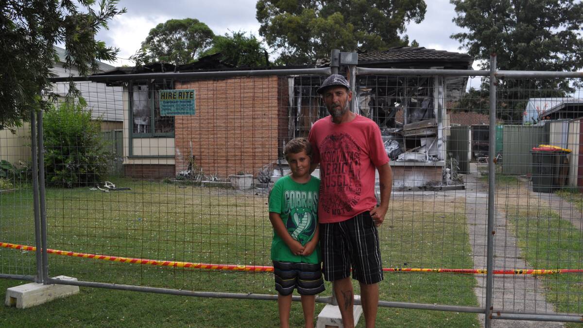 GUTTED: Rodney Macfarlane and nine-year-old Zack in front of the ruins of their former home in Galloway Street, Kurri