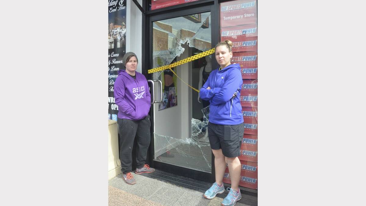 SMASHED: Sportspower Cessnock staff Tara Herring and Inga Connors at the Vincent Street store's damaged front door on Wednesday morning.