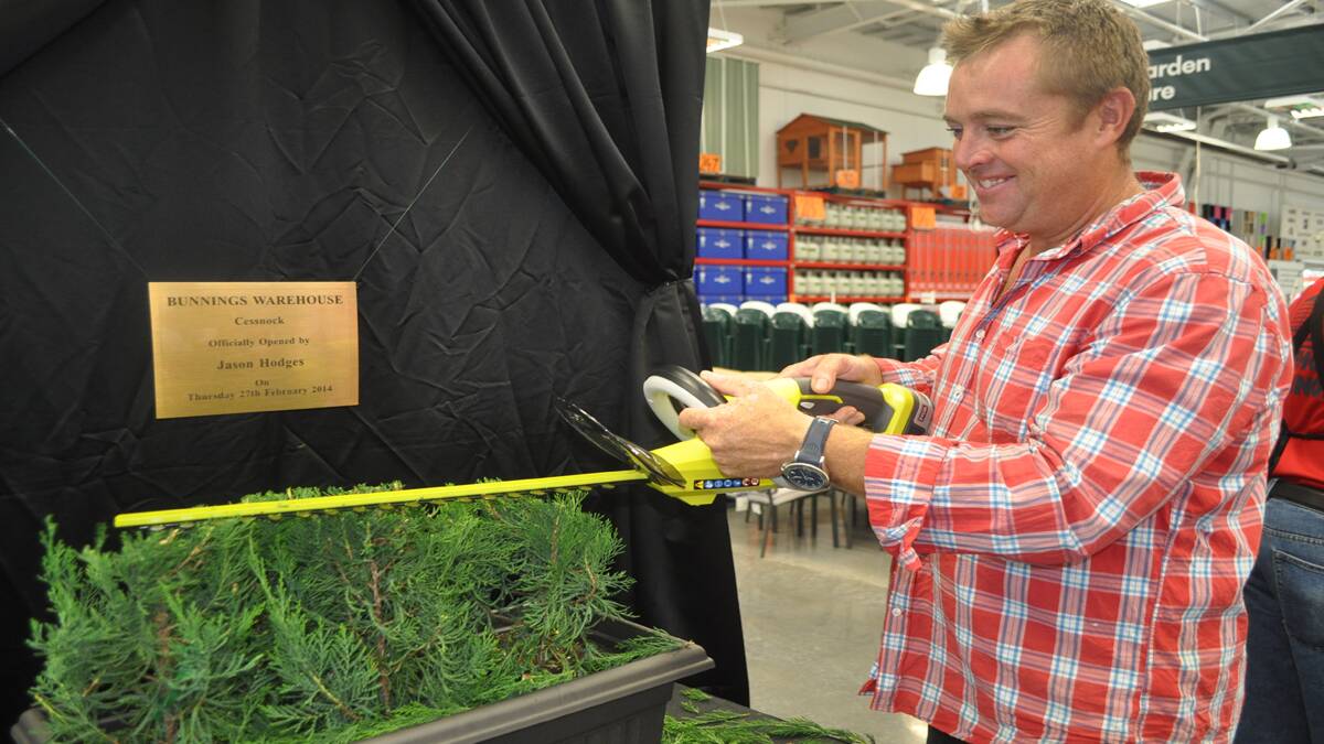 Jason Hodges trims the hedge to unveil a plaque commemorating the stores opening. 