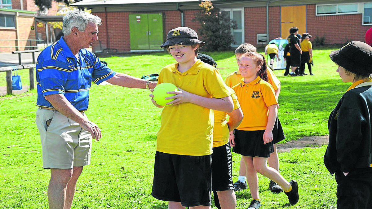 Don Stephens from the Bradman Foundation helps out Cessnock Public School student Blake Kegan in one of the Dream Cricket activities. 