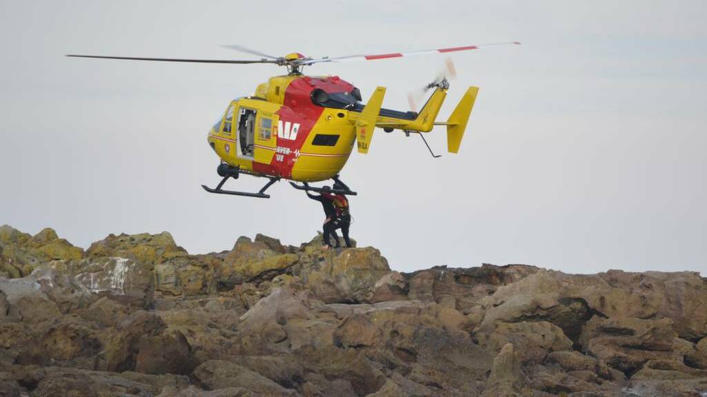 A helicopter collects a man and his daughter from a rocky outcrop off North Narrawallee Beach. 