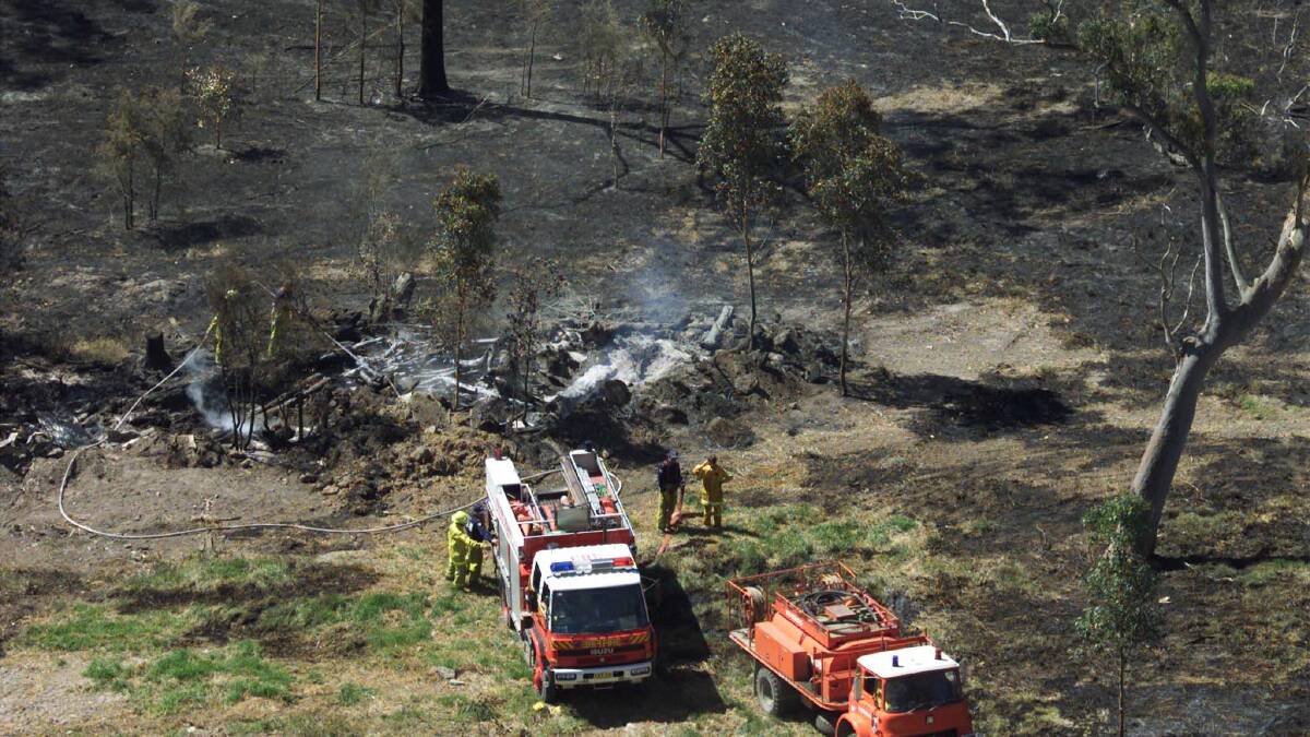 Firefighters douse flames on smouldering bushland near the central coast town of Wyong in 2001. Photo: REUTERS