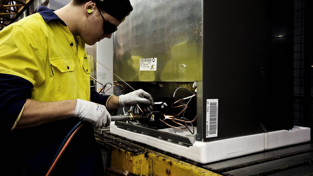 An employee of Electrolux adds components to a fridge at the Electrolux Factory. Photo: DOMINIC LORRIMER 