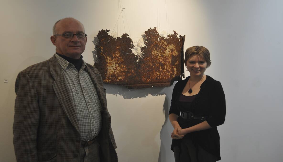 HAPPY: Cessnock Regional Art Gallery director John Barnes and gallery assistant Christiana McDonald-Spicer with a piece from the gallery’s latest exhibition, Steel Seams.