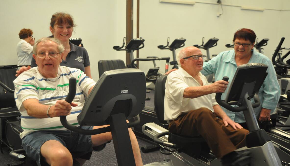 Working out on the exercise bikes at Total Fitness are Integrated Living clients Paul Laskey with Alayne Rohr and Bernard Bruce with Dementia Advisory Service carer Barbara Dawson. 