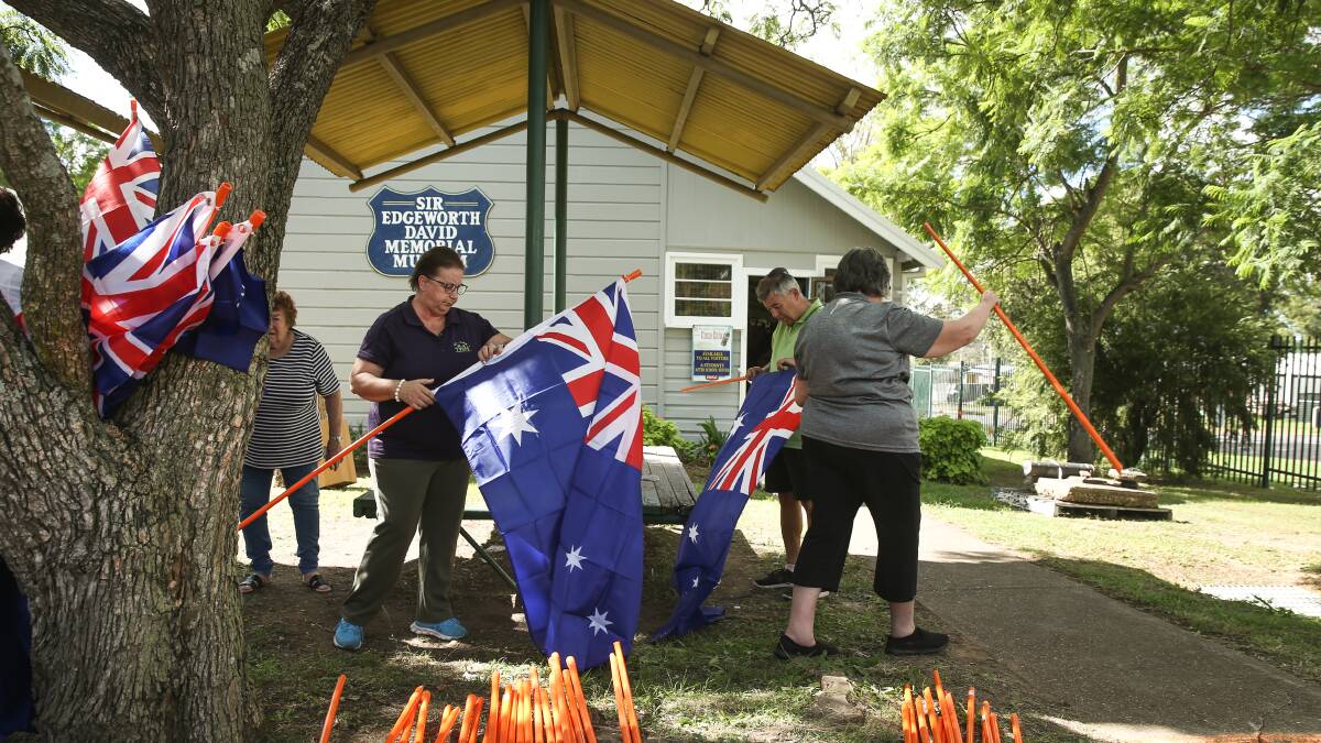 Volunteers preparing the Australian flags, which will be placed on the graves of local Anzac soldiers.