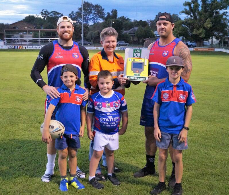 LIFE SAVERS: Bulldogs players Mitchell Cullen, Mick Campton and Bulldogs juniors Mac Peterkin, Ollie and Darcy Campton with Austar Cole Mine representative Carly McCormack at the presentation of the defibrillator unit.