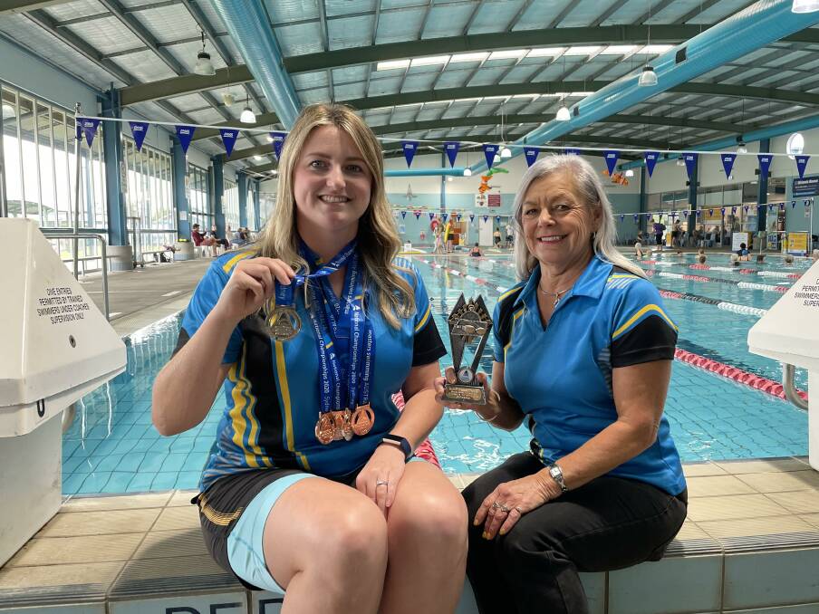 ACHIEVEMENT: Lindsey Creed with her medals from the Masters Swimming Australia national championships, and Diane Partridge with her meritorious service trophy.