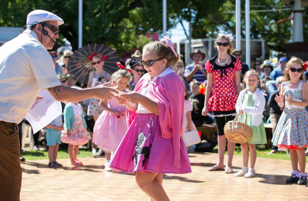 STYLE: Charlotte Perkins receiving her prize from DJ Gav in the Junior Best Dressed Competition at the 2019 Kurri Kurri Nostalgia Festival. This year's best dressed competitions will be held at Weston Workers Club and livestreamed on Facebook. Picture: Angela Hardy Photography