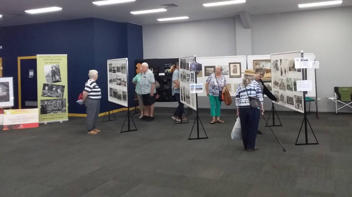 EXHIBITION: Visitors to the Town of Murals Art and Craft Festival checking out the display of photographs from the Sir Edgeworth David Memorial Museum.