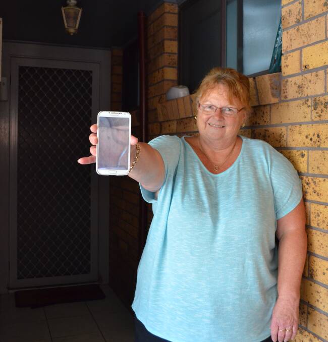 FRIGHT: Kurri Kurri resident Louise Harmey with a photo of the snake that was first spotted at her back door, then in her bedroom two days later. Picture: Krystal Sellars
