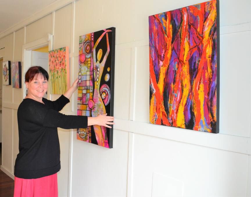 EXCITED: Emmie Hallett hangs one of Valerie Maude's paintings in the gallery that will open soon at Wild Learning. Picture: Krystal Sellars