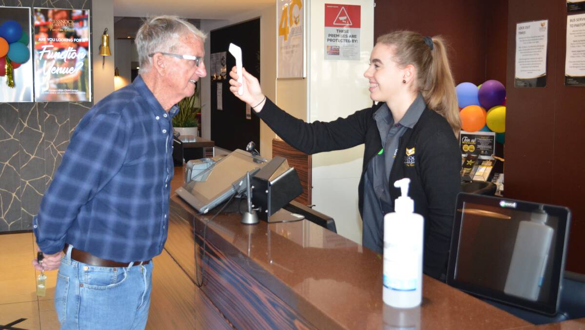 SAFETY MEASURES: Garry Harding, of Orange, has his temperature taken by receptionist Rachael Trudgett at Cessnock Leagues Club on Friday.