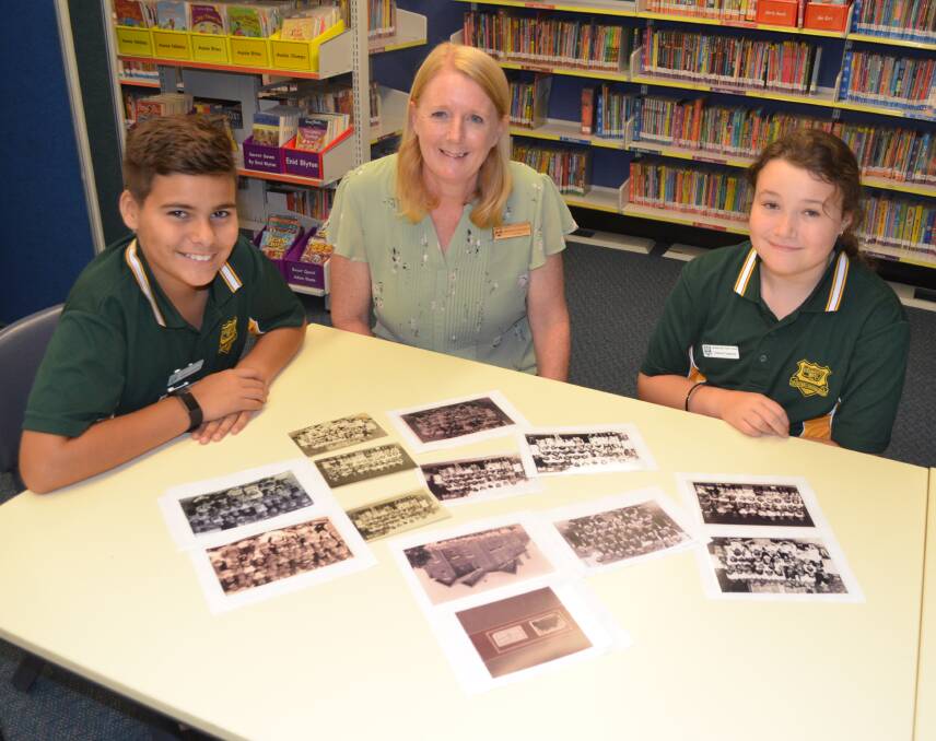 HISTORY: Cessnock West Public School principal Ruth Goodwin and captains Maliyan Donovan and Tayla Cox look over old photos ahead of the school's centenary in March.