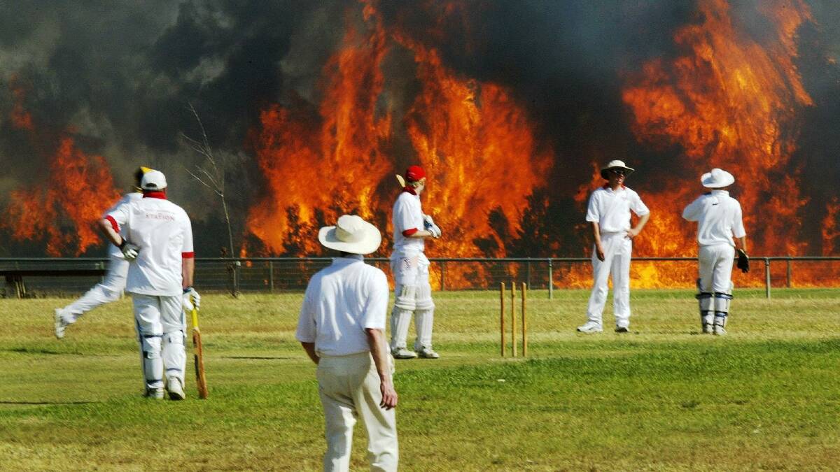 ICONIC IMAGE: Darren Pateman's Walkley-award winning photograph of the cricket match that took place at Cessnock as the bushfire approached in October 2002.