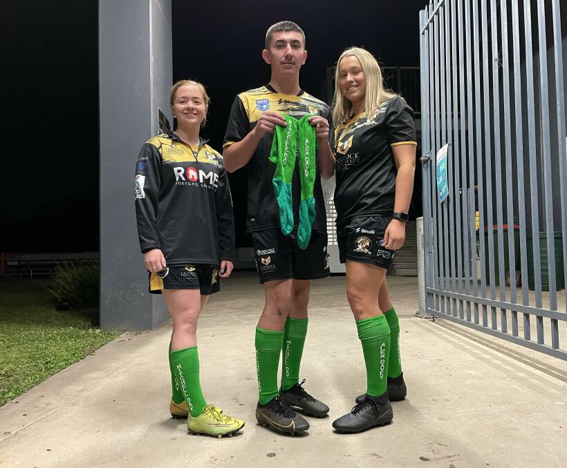 GOOD CAUSE: Cessnock Goannas players Olivia Rostron, Noah Rootes and Jorja Southwell with the green socks the Goannas will wear this Saturday. Picture: Krystal Sellars