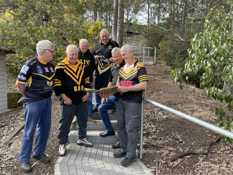 GOOD TIMES: Pictured at the Convent Hill steps where they used to run "three to five laps" every training session, the Goannas Old Boys take a look at Dennis Moore's scrapbook from the 1972 season. Picture: Krystal Sellars