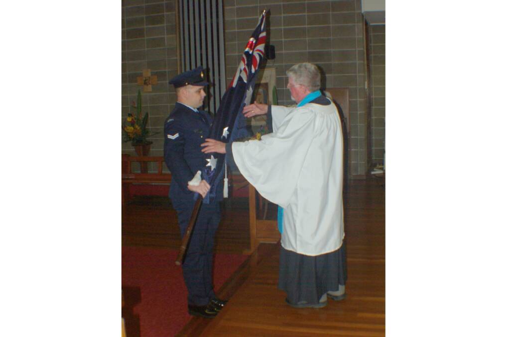 TRADITION: Kurri-born Corporal Struan Dyson-Smith presents the Australian national flag to Fr Carl Lanham at the 2017 Anzac Day commemorative service.