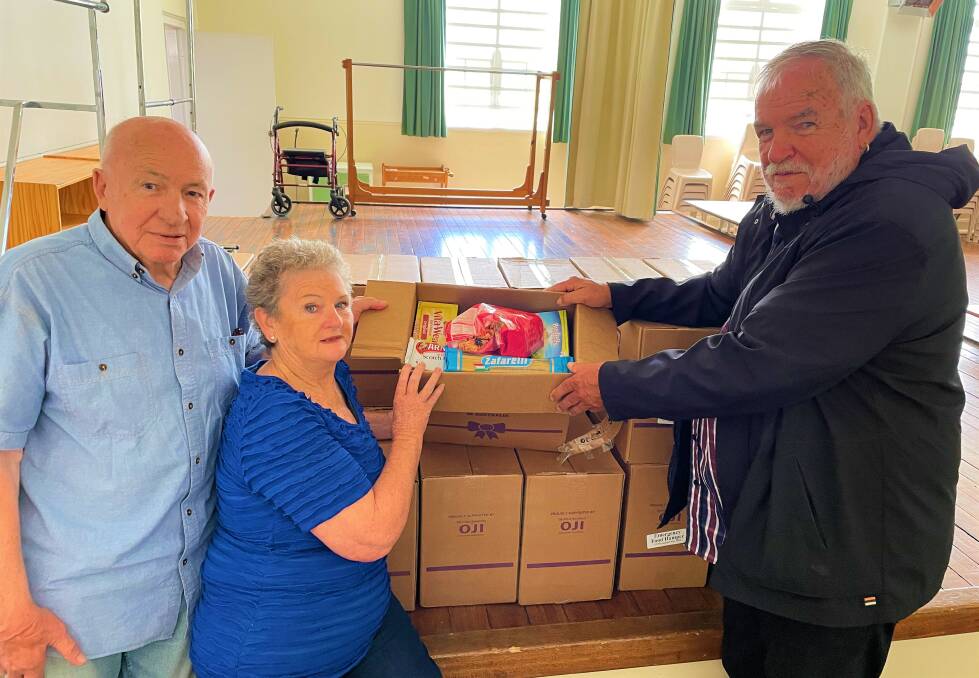 HELPING HAND: Cessnock Christian Christmas Day Luncheon committee members Robert and Helen Dyball and Reverend Neil Smith of Cessnock Uniting Church, with some of the Foodbank hampers that will be distributed this Christmas.