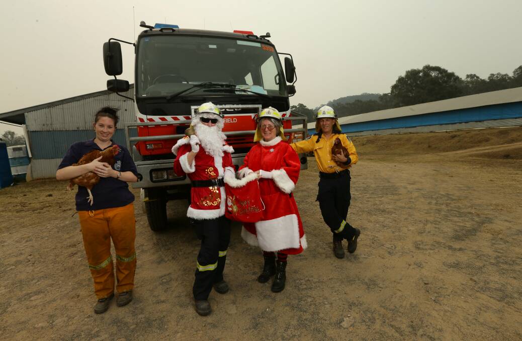 LOOKING FOR LAND: Millfield RFS volunteers Candice Craig (holding Bolt the chicken), Jenny Beveridge, Fi Eason, and Peter Beveridge (holding Olivia) in front of their station, a former chicken shed, before the brigade's Santa run on Sunday. Picture: Jonathan Carroll