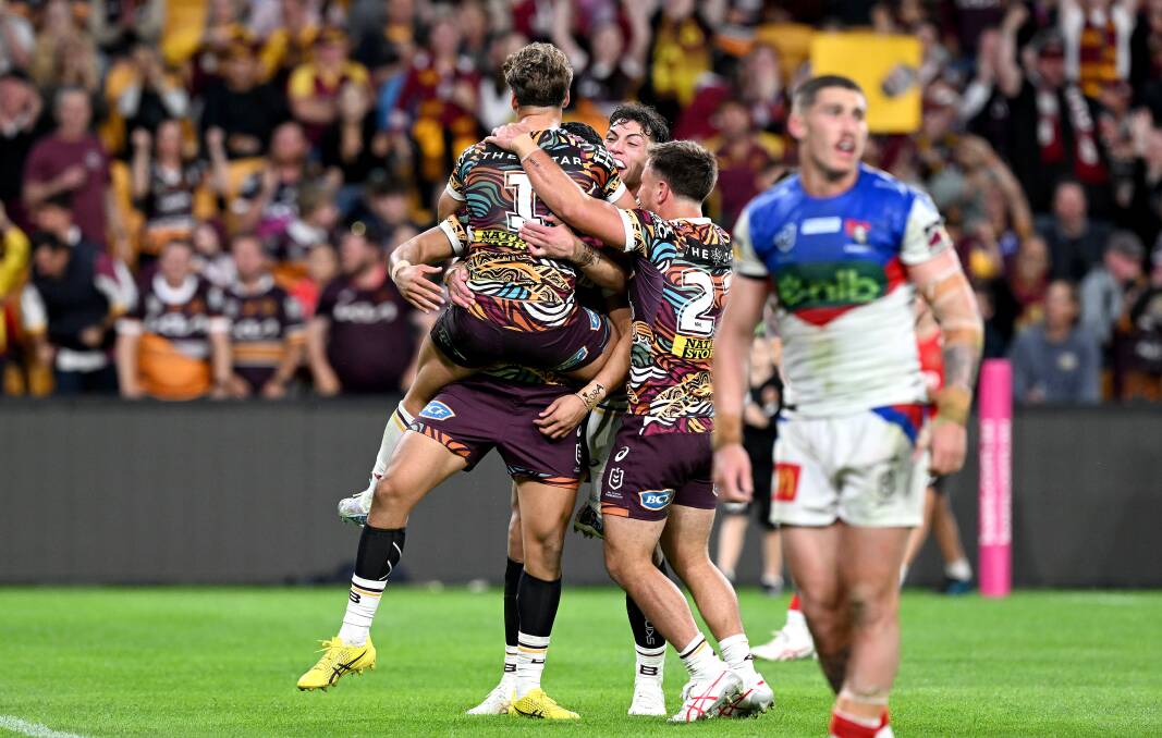 Brendan Piakura is congratulated by his Brisbane teammates after scoring against Newcastle. Picture Getty Images