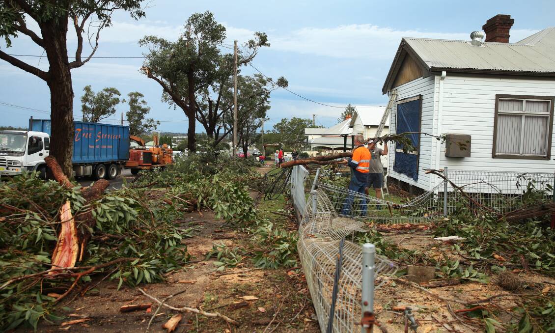 Downed: Residents of Main Street, Kurri Kurri clear piles of branches which fell during the storm, damaging houses, powerlines and fences. Picture: Marina Neil