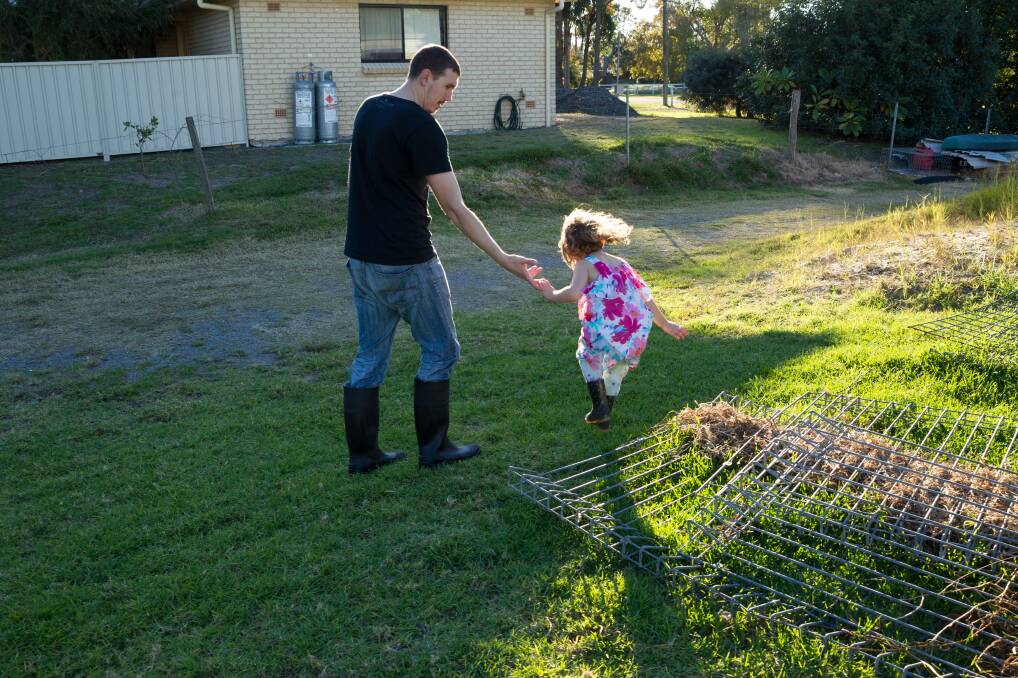 CAUGHTOUT: Ryan Baker and his daughter Ociana in the backyard of their home at Salt Ash. Mr Ryan is unable to take out a business loan because his house is in the red zone. Picture: Max Mason-Hubers