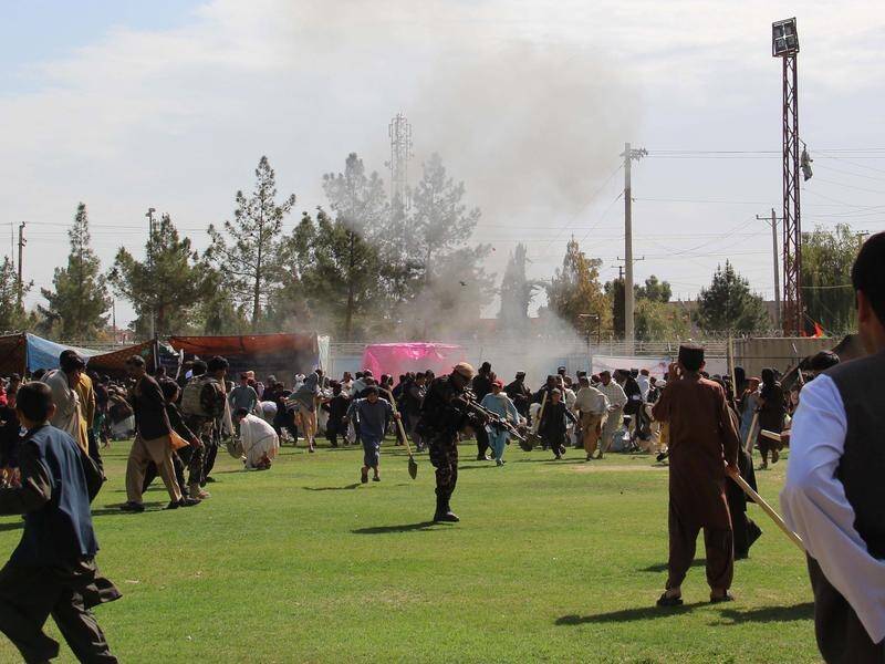 People react after twin bomb blasts at the Farmers Day ceremony in Helmand province, Afghanistan.