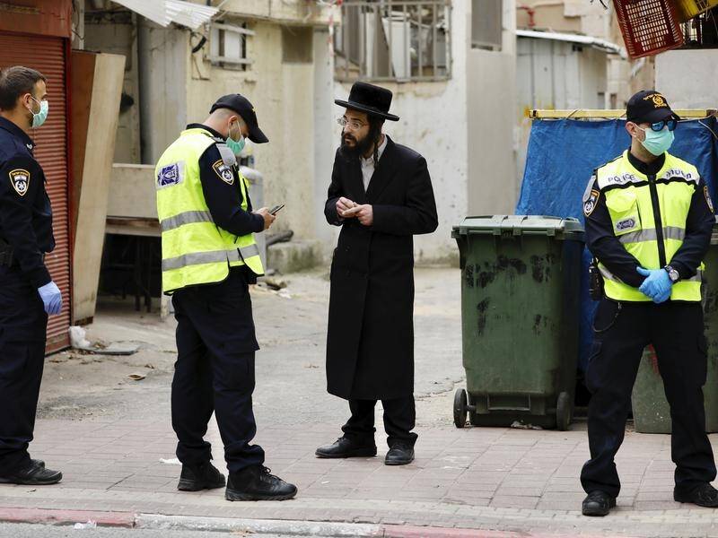 An ultra-Orthodox Jewish man is questioned by police in the Tel Aviv suburb of Bnei Brak.