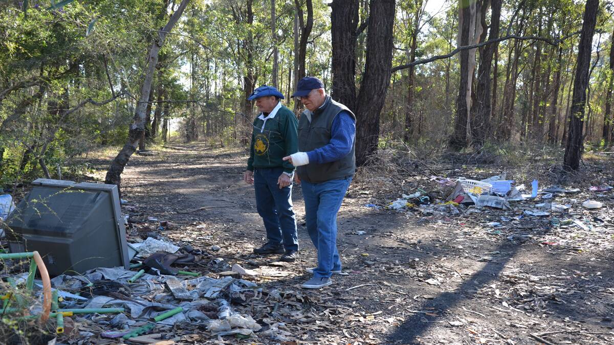 DISGRACE: Kurri Tidy Towns volunteers Bob Burns and Bill Way inspect the rubbish that has been dumped on the Kooka­burra Walk.